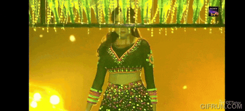 a woman in a crop top is dancing in front of a sign that says giffruit.com