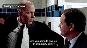a man in a suit and tie is talking to another man .