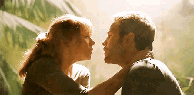 a man and a woman are kissing in the jungle .