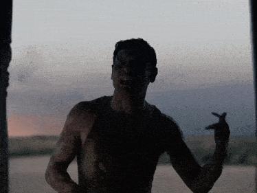 a man without a shirt is standing in the dark