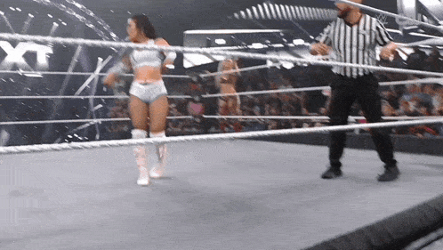 a referee stands in a wrestling ring next to a woman in a white outfit