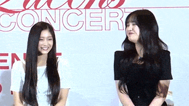 two young women are standing next to each other and smiling in front of a sign that says concert .