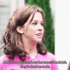 a woman in a pink shirt says make sure you check out her mom 's boob job