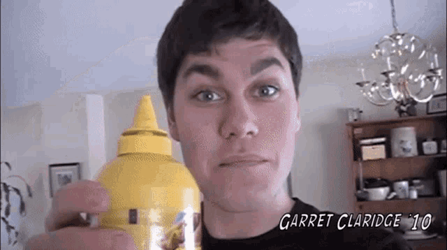 a man is holding a bottle of garret claridge 10 mustard
