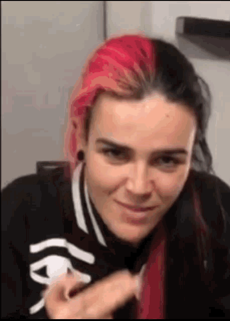a woman with pink and black hair is smiling and holding something in her hand