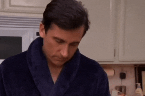 a man wearing a blue robe looks down in a kitchen