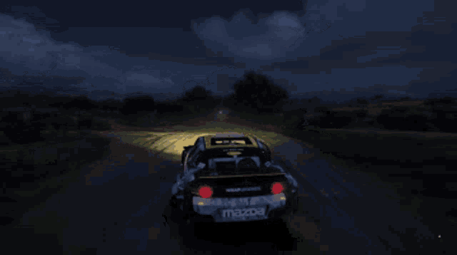 a mazda car is driving down a dirt road