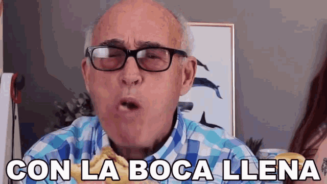 a man wearing glasses and a plaid shirt says " con la boca llena " in spanish
