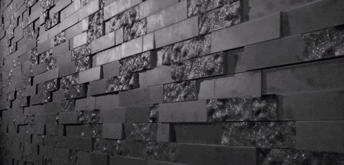 a black and white photo of a black brick wall