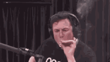 a man is smoking a cigarette in front of a microphone and smoke is coming out of his mouth .