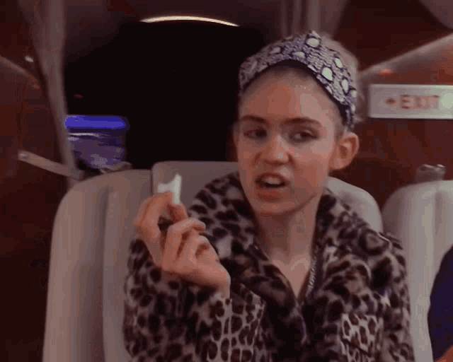 a woman wearing a leopard print coat is sitting in front of an exit sign