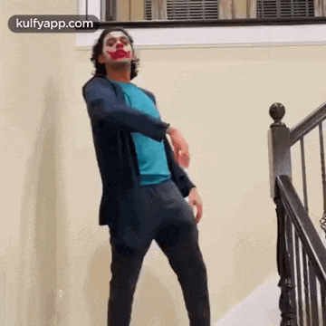 a man dressed as the joker is standing on a set of stairs .