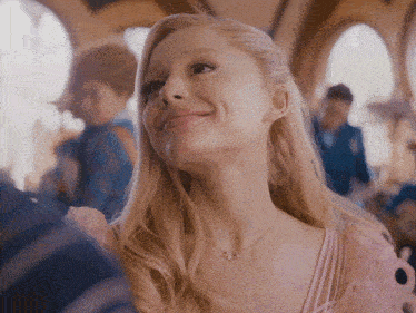 a woman in a pink dress is smiling and wearing a necklace with a butterfly on it