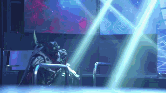 a man in a costume is sitting in a dark room with blue lights shining on him