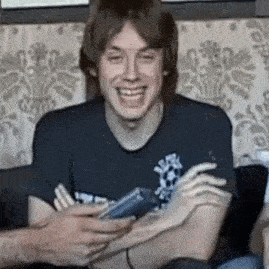 a young man is laughing while holding a cell phone .