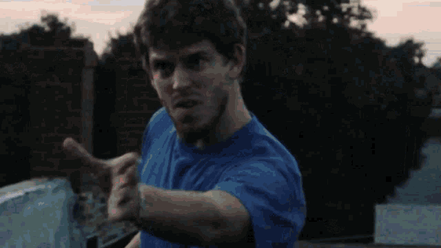 a man in a blue shirt is pointing his finger at the camera