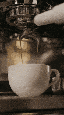 a cup of coffee is being poured from a coffee machine