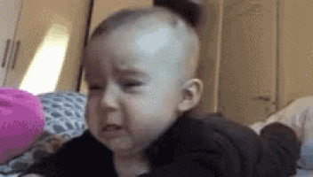 a baby is crying while laying on a bed .