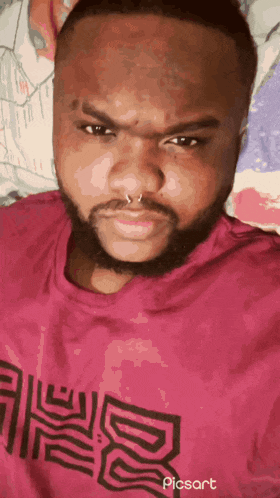 a man with a beard and a nose ring is wearing a pink shirt that says picsart