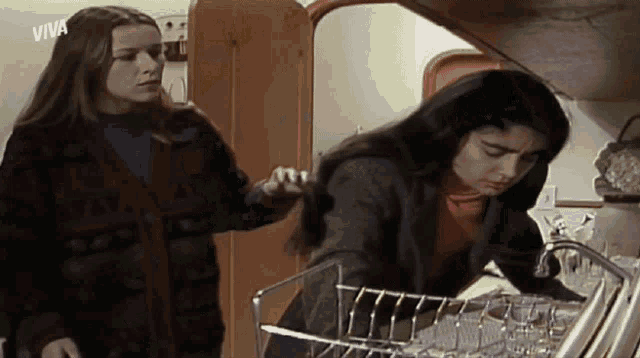 two women are standing in a kitchen with the word viva on the bottom