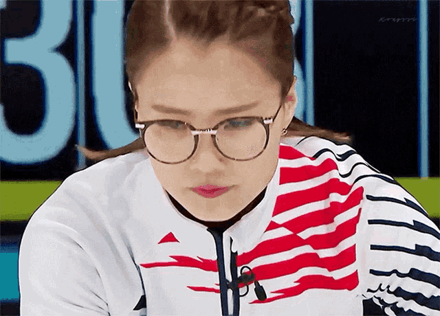a woman wearing glasses and a red white and blue striped shirt with the number 30 in the background