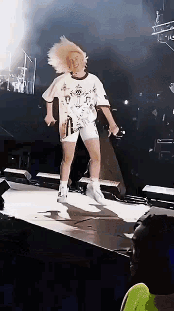 a woman with blonde hair is dancing on a stage with a microphone in her hand .