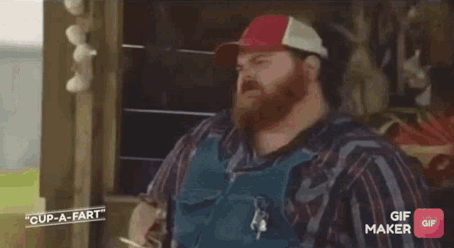 a man with a beard wearing overalls and a red white and blue hat says cup-a-fart
