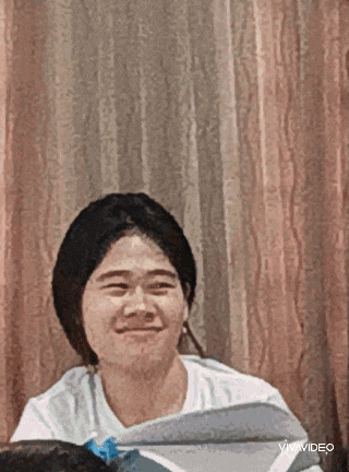 a young man is sitting in front of a curtain and smiling .
