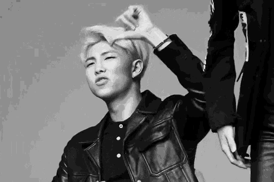 a black and white photo of a man in a leather jacket being touched by another man .