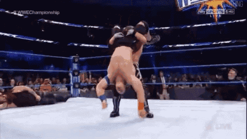 two men are wrestling in a wrestling ring and one of them has his pants down