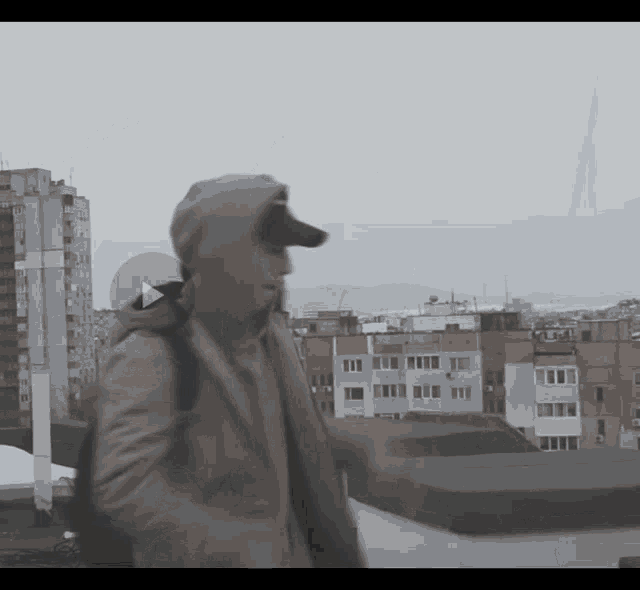 a man in a hooded jacket is walking in front of a cityscape