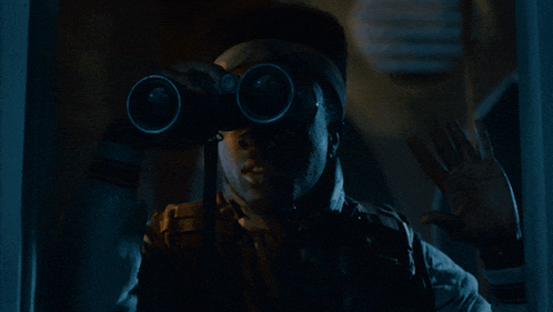 a man is looking through binoculars in a dark room and waving