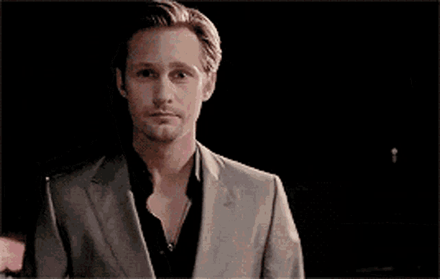 a man in a suit looks at the camera with a serious look on his face