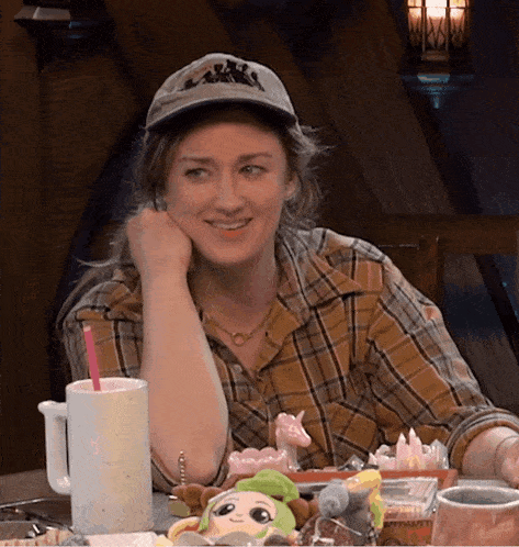 a woman sitting at a table with a hat that says ' new york '