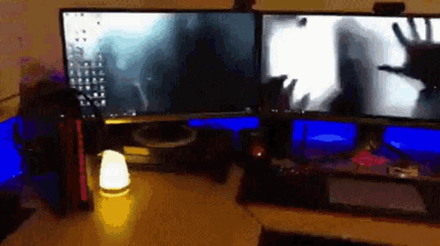 two computer monitors are sitting on a desk with blue lights
