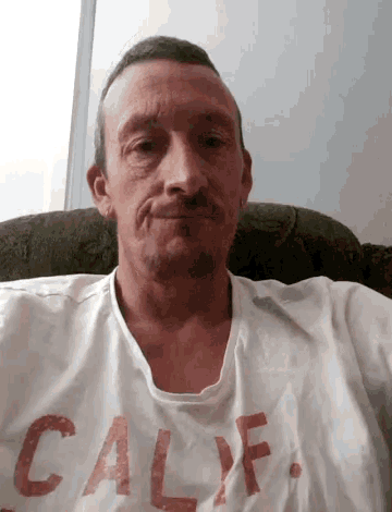 a man is sitting in a chair wearing a white california shirt