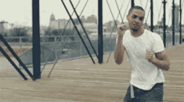 a man in a white t-shirt is running on a bridge .