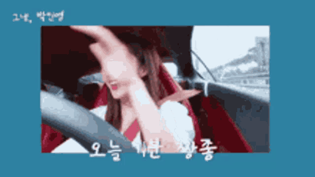 a woman is driving a car with chinese writing on the bottom