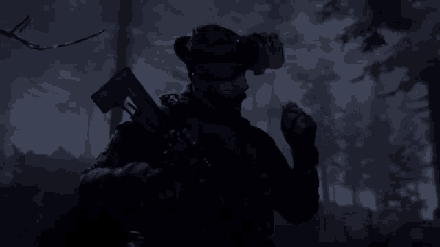 a man in a military uniform is holding a gun in the dark
