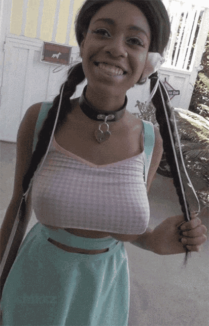 a woman wearing a choker and braids smiles in front of a sign that says no dogs allowed