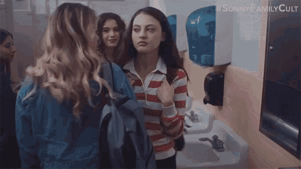 a woman with a backpack is walking down a hallway with other girls .