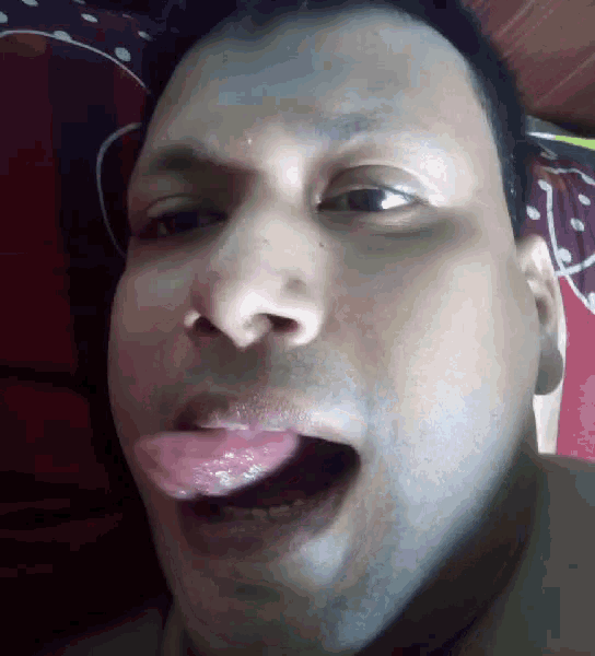 a man with his tongue sticking out looks at the camera