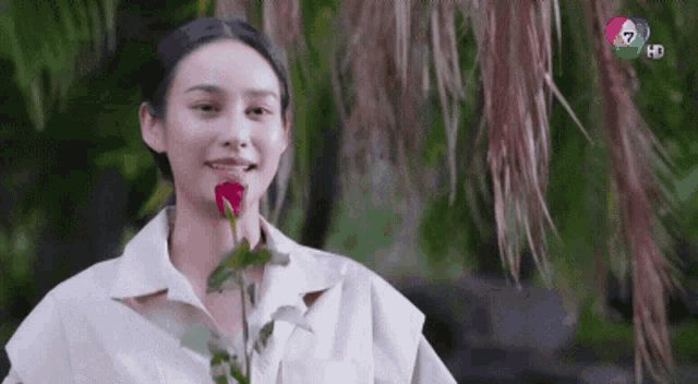 a woman is holding a rose in her mouth .