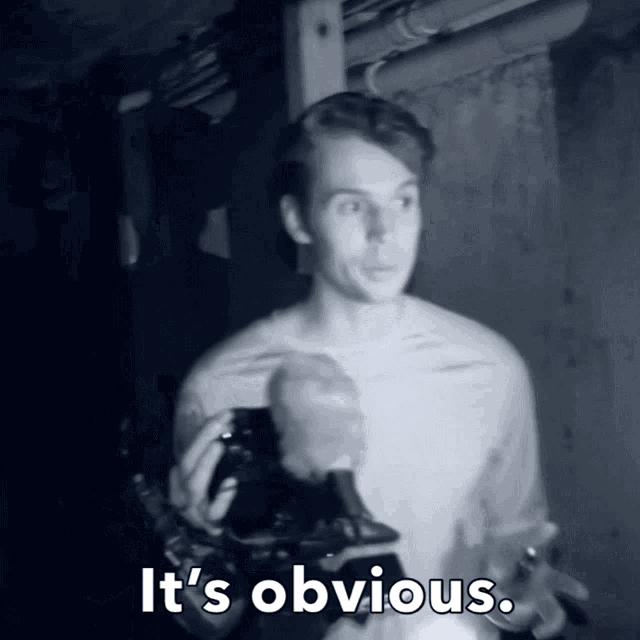 a man in a dark room with the words it 's obvious above him