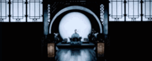 a blurry picture of a man sitting in front of a large circle