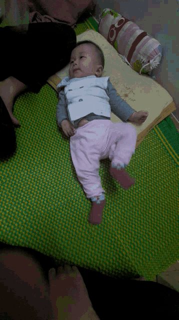 a baby is laying on a green mat with a pillow that says ' a ' on it