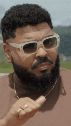 a man with a beard wearing sunglasses and a gold chain around his neck