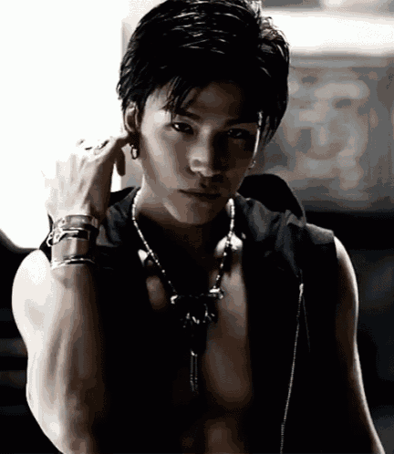 a shirtless young man wearing a necklace and bracelets