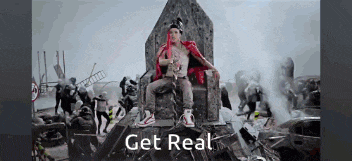 a man in a red jacket is sitting on a throne with the words get real below him