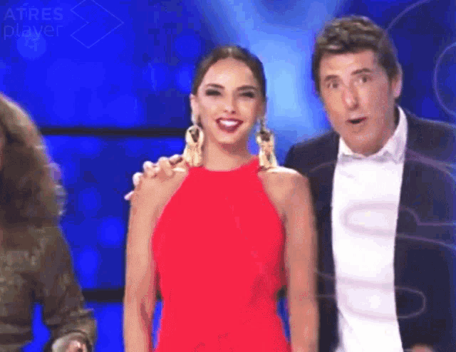 a woman in a red dress is standing next to a man